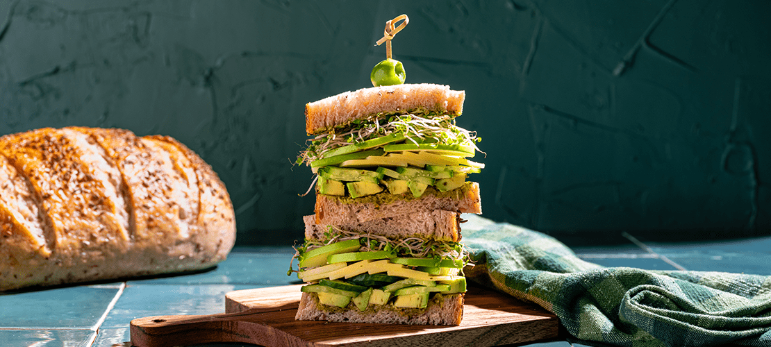 Stacked halves of a St. Patrick's Day inspired sandwich on artisan bread with a green background and green handtowl