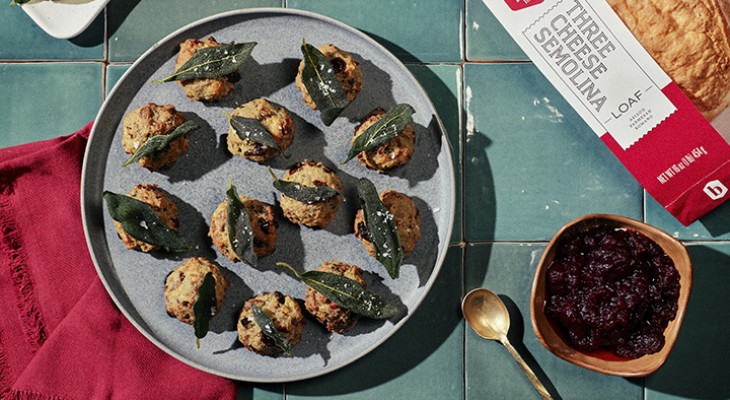 12 Semolina cheese stuffing balls plated on a slate colored serving dish sitting on a green tile counter top with red napkins