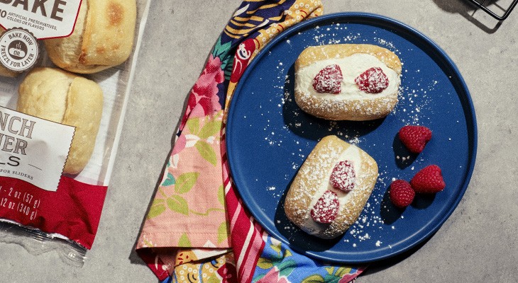 two prepared dinner rolls filled with cream and berries