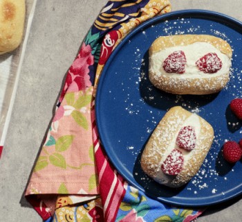 two prepared dinner rolls filled with cream and berries